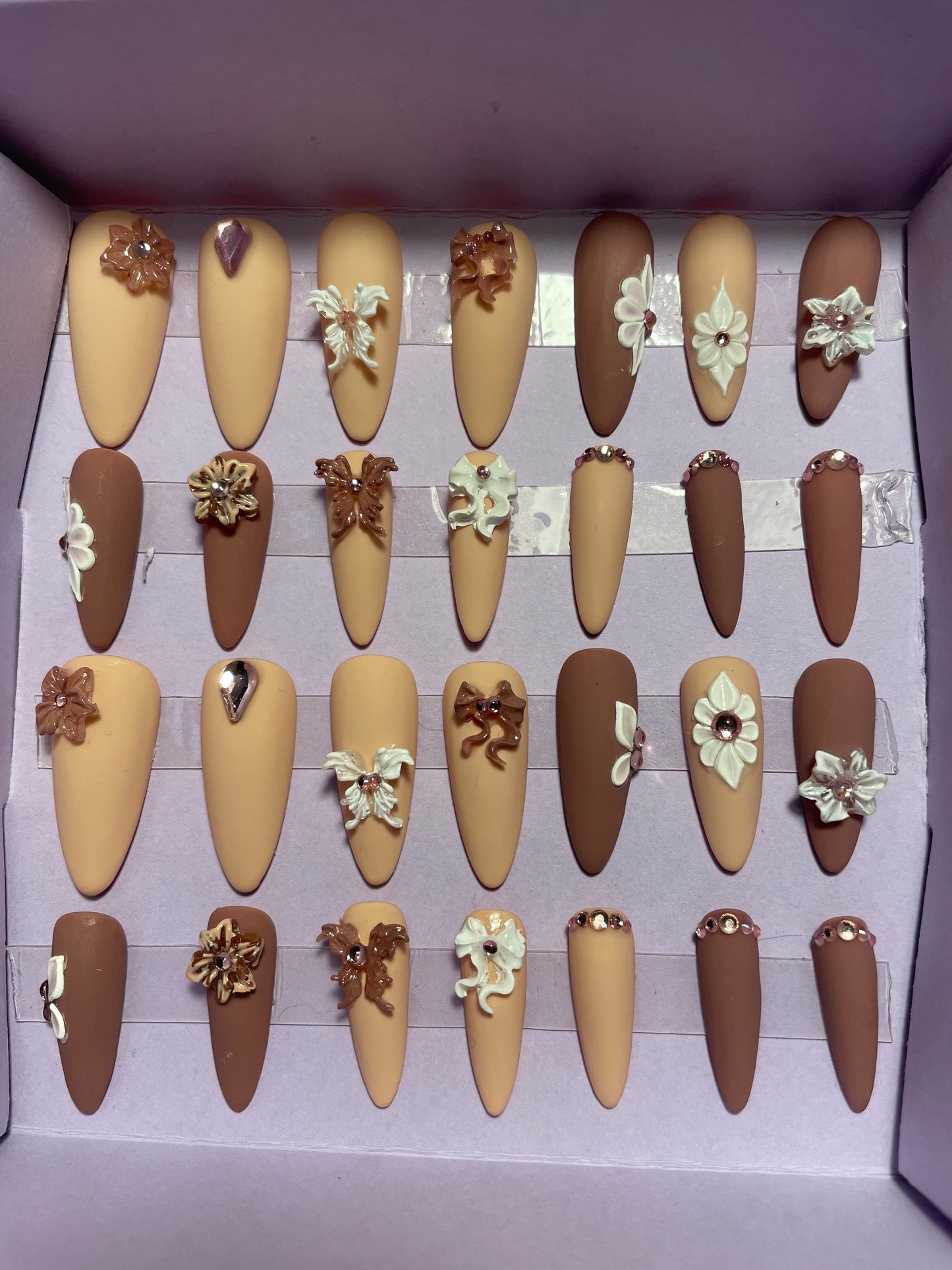 Beige/cacao avec fleurs et noeuds en relief. Kit complet toutes tailles incluses. Réutilisables. Press-on nails, faux ongles. Finition mate
