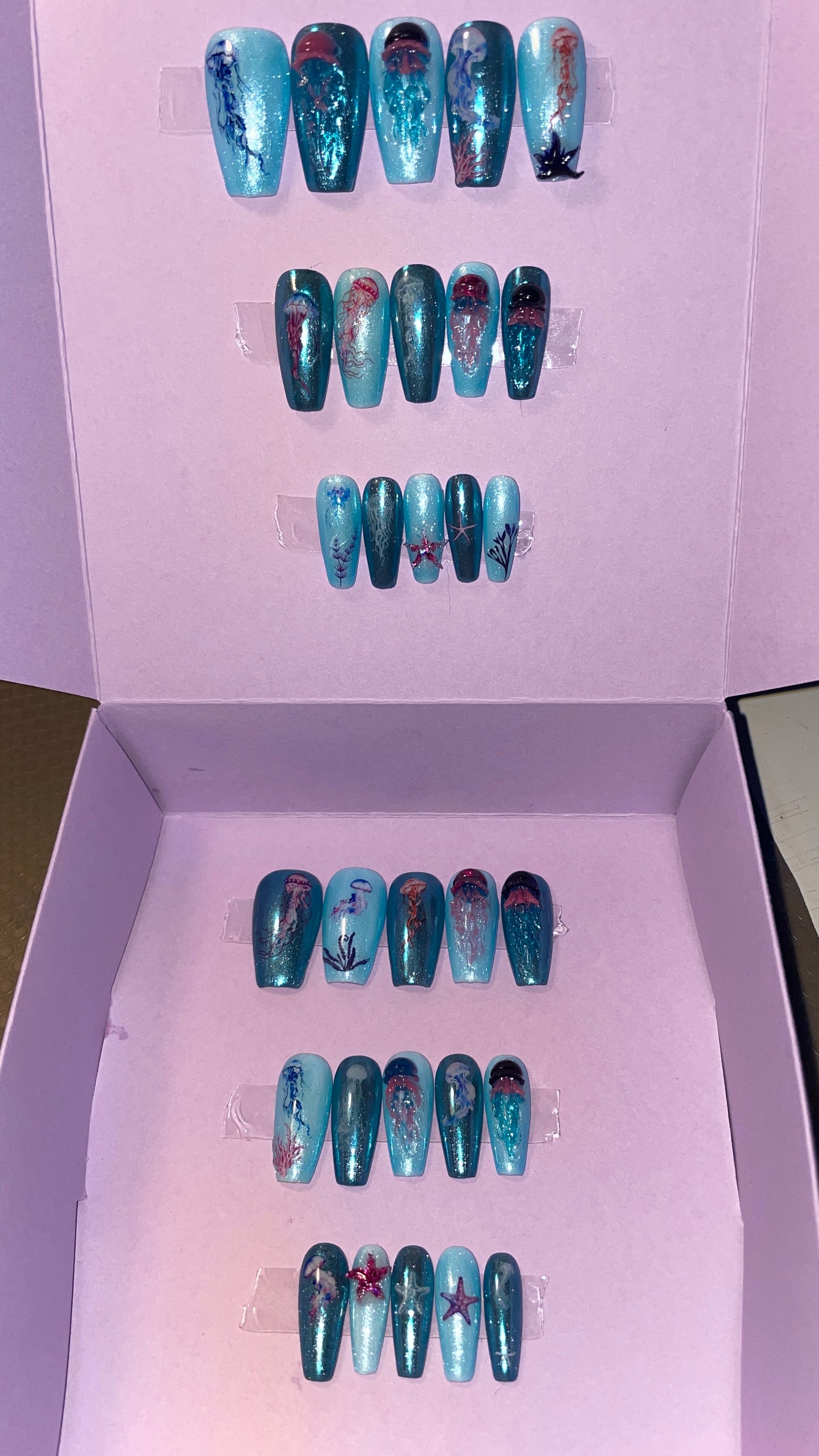 Kit complet. Toutes tailles incluses. Bleu métallisé avec petites méduses en relief. Réutilisables. Press-on nails, faux ongles. Fini brillant
